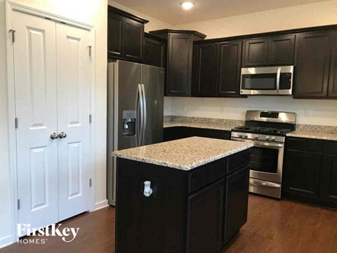 a kitchen with black cabinets and granite counter tops and stainless steel appliances