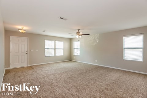A spacious room with a carpeted floor and a ceiling fan.