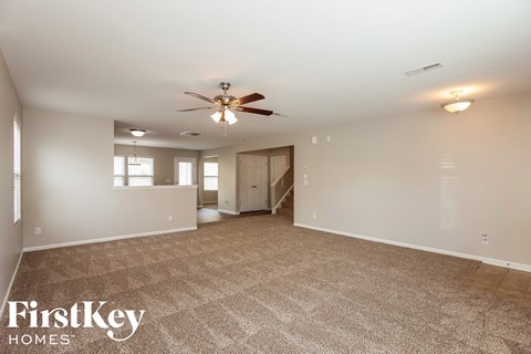 A spacious room with a carpeted floor and a ceiling fan.