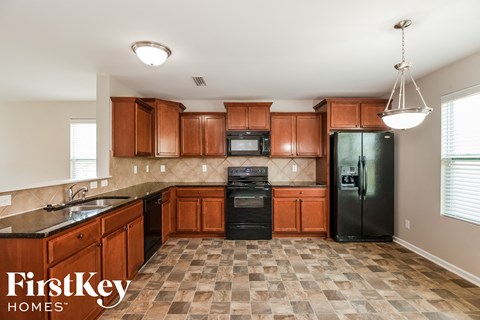 A kitchen with wooden cabinets and a black refrigerator.