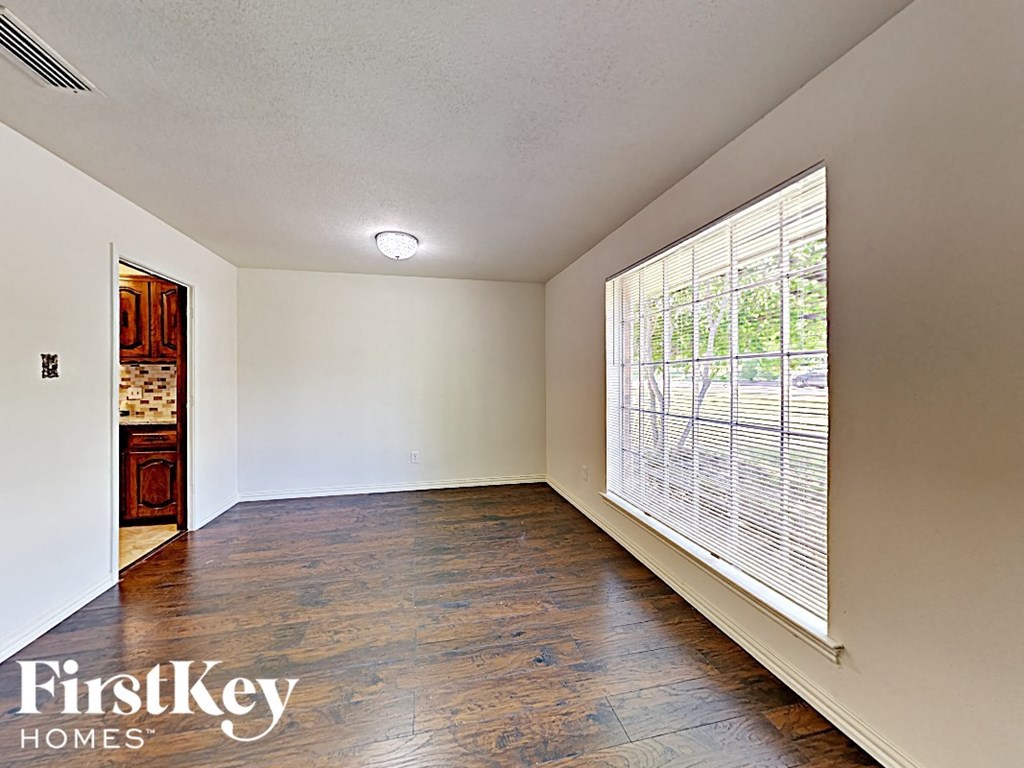 A room with wooden floors and a window with blinds.