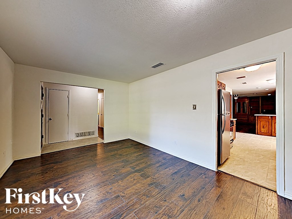 A room with wooden floors and a doorway leading to another room.
