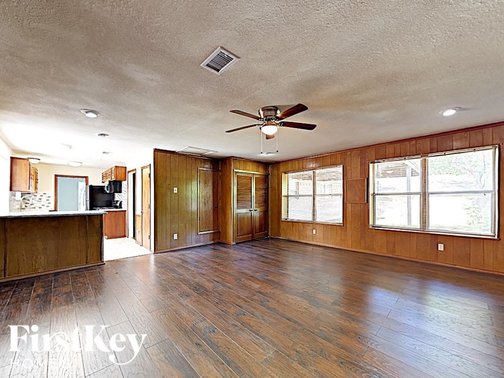 A spacious room with wooden floors and a ceiling fan.