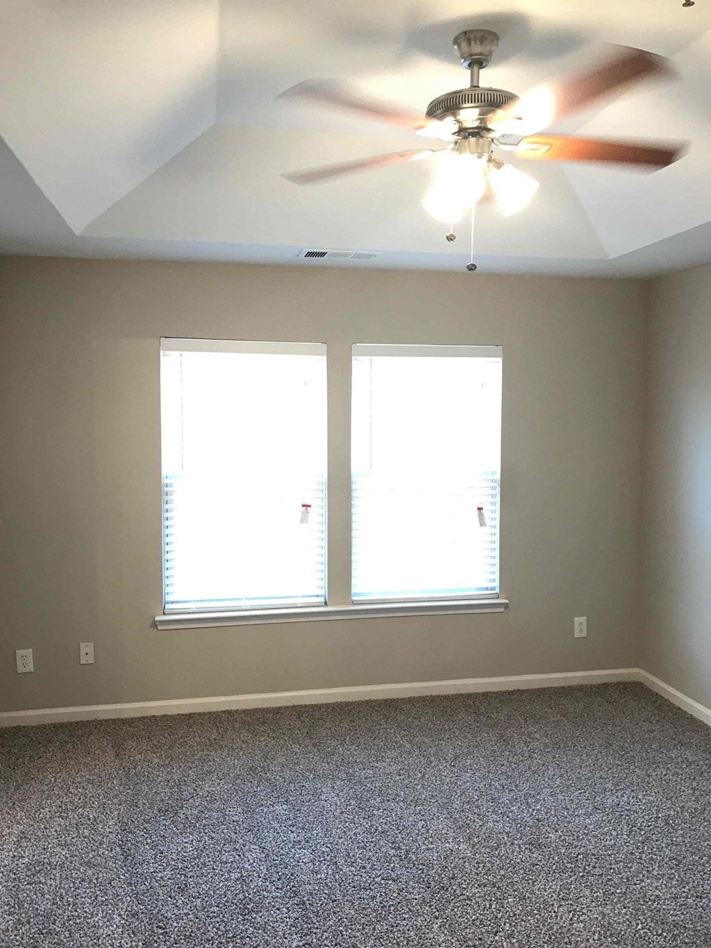 a living room with a ceiling fan and two windows