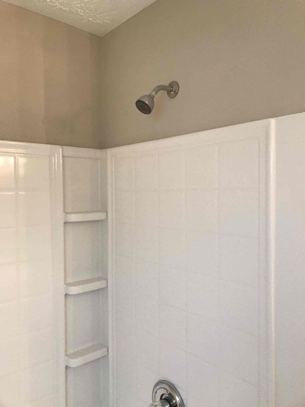 a bathroom with a shower and a white tiled wall