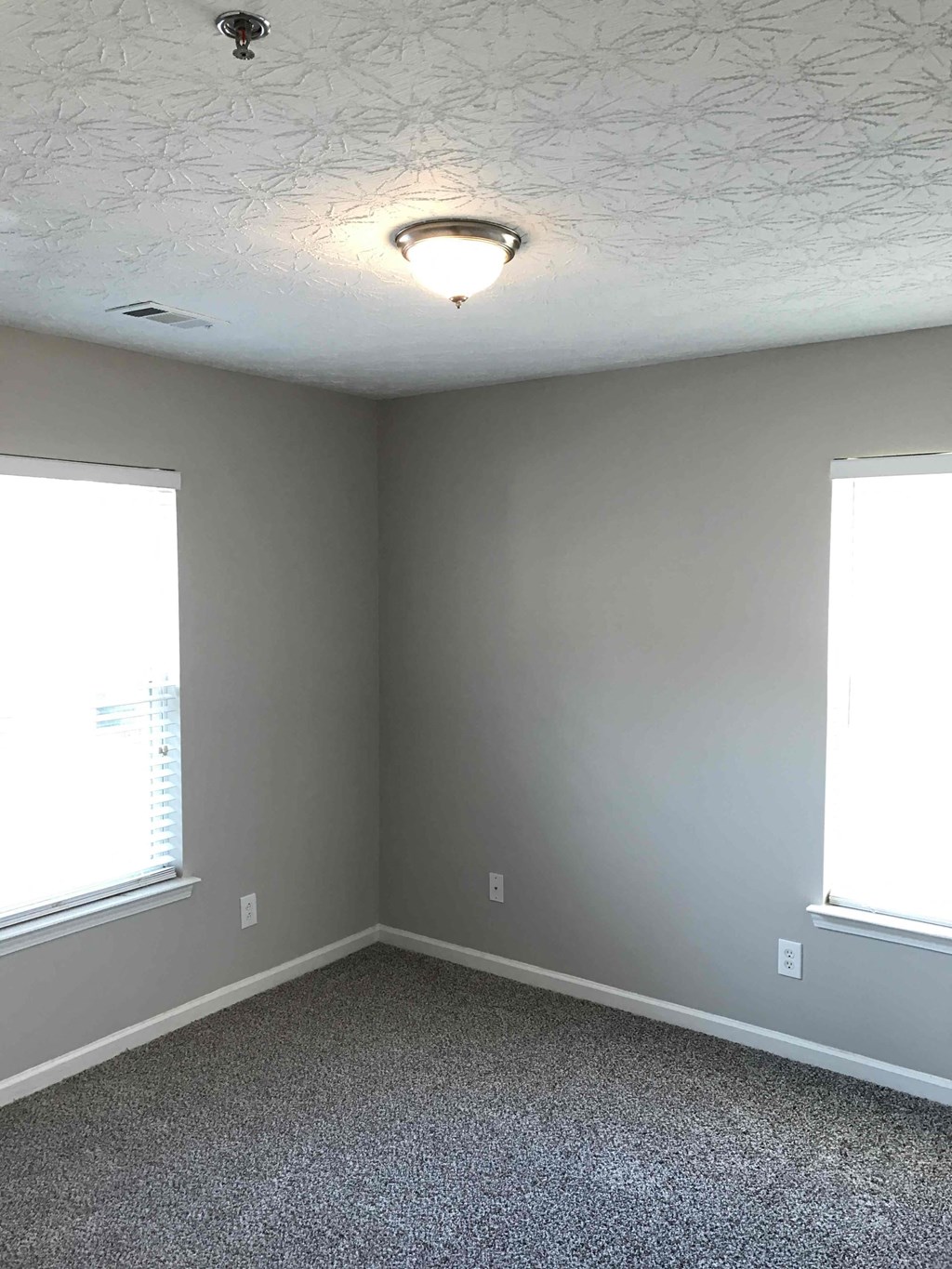 a room with two windows and a light on the ceiling