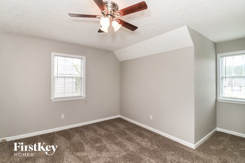 the living room of a home with carpet and a ceiling fan