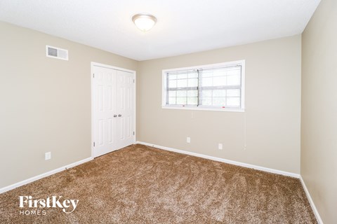 a bedroom with carpet and a white door and window