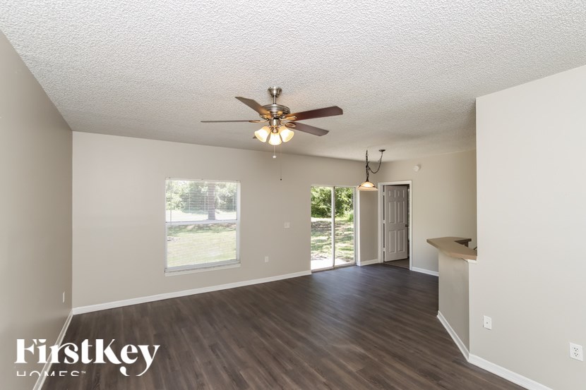 A spacious room with a ceiling fan and a window overlooking a green area.