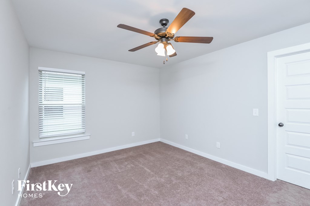 a bedroom with a ceiling fan and a carpet