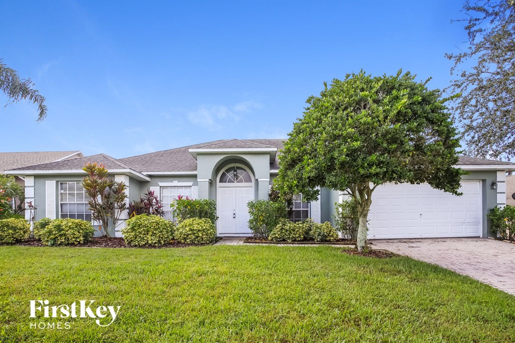 A house with a white garage door and a tree in front.
