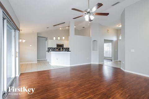 A spacious living room with a wooden floor and a ceiling fan.
