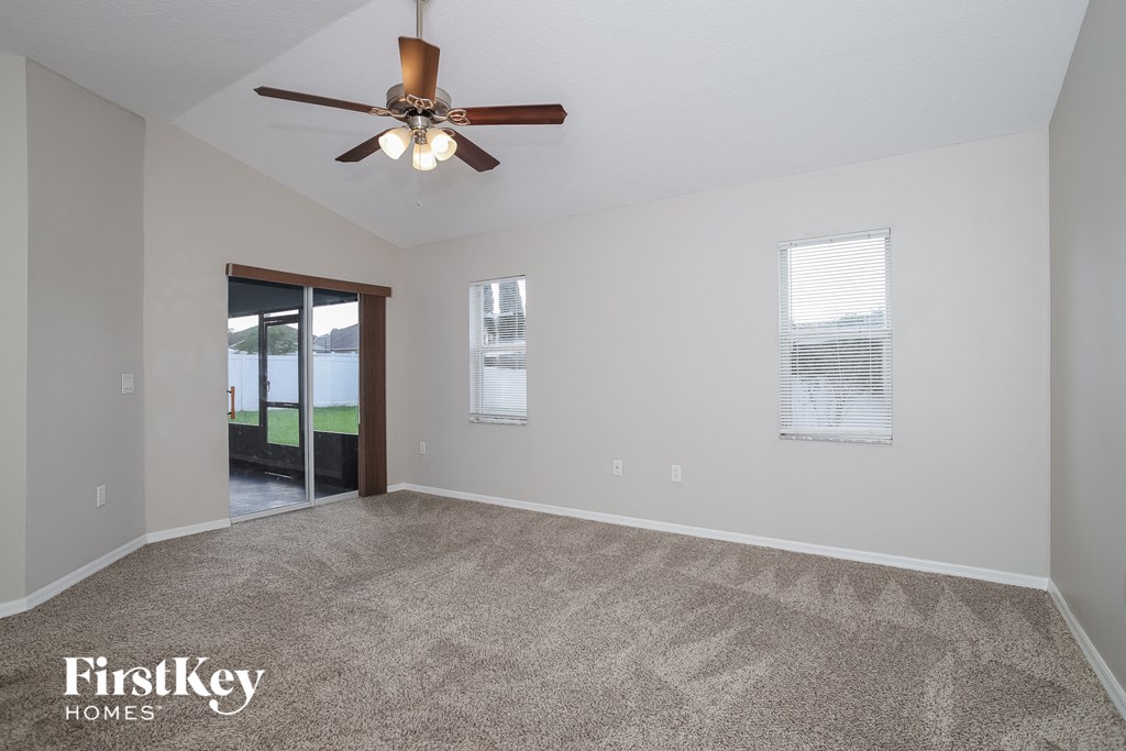 A spacious room with a ceiling fan and two windows.