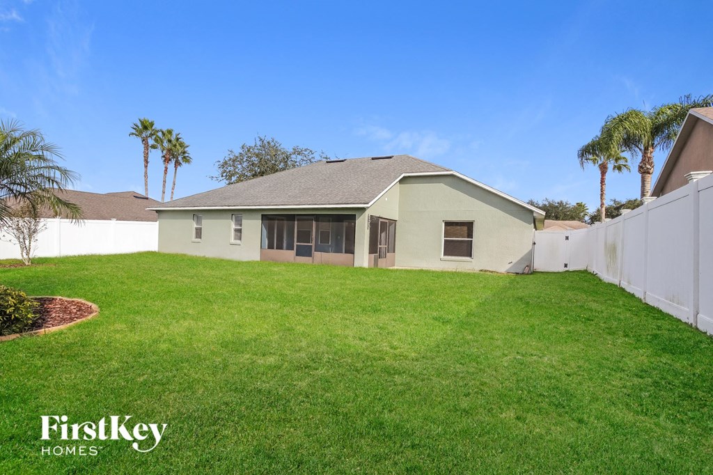 A house with a lawn and palm trees in the background.