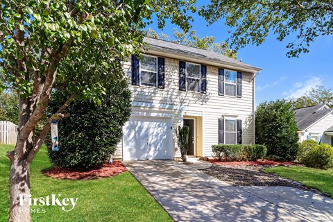 a white house with a white garage door and a tree