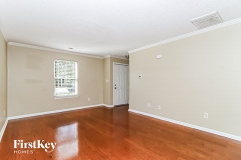 the living room of a house with wood floors and white walls