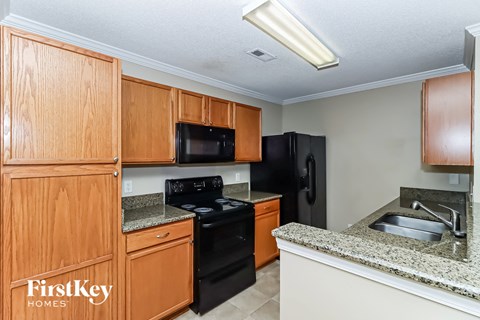 a kitchen with black appliances and wooden cabinets and granite counter tops