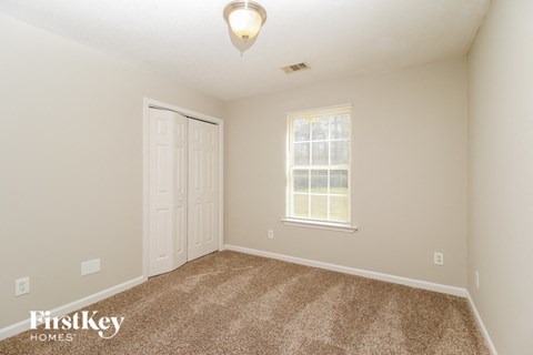 a bedroom with carpet and a door and a window