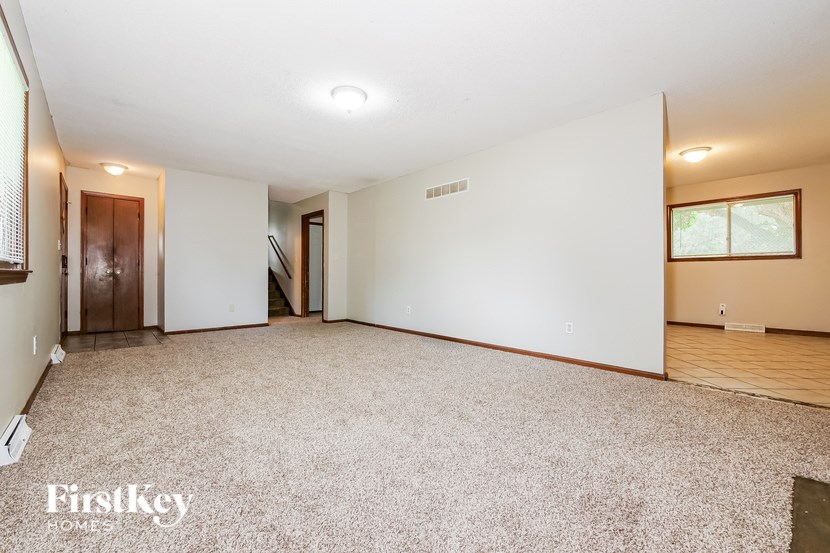 A spacious room with a carpeted floor and a window.