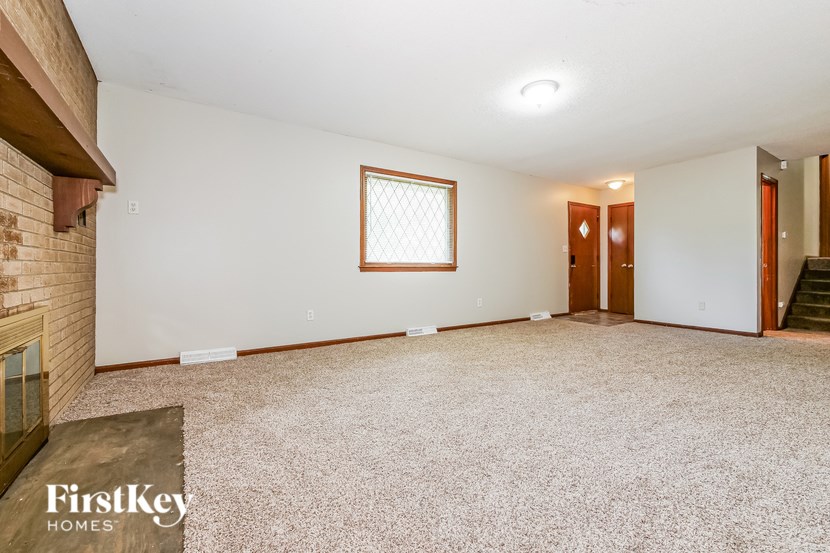 A room with a carpeted floor and a window with bars on it.