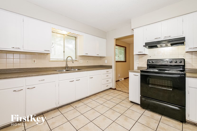 A kitchen with white cabinets and a black oven.