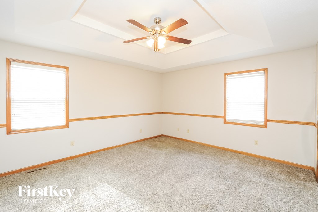 a living room with two windows and a ceiling fan