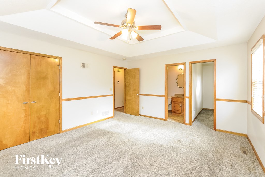 a master bedroom with a ceiling fan and a carpeted floor
