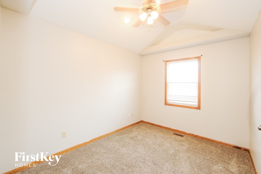 a bedroom with white walls and a ceiling fan and a window