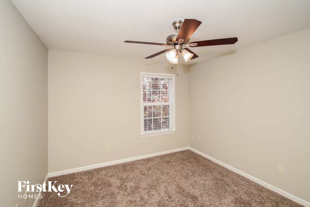 a bedroom with a ceiling fan and a carpet