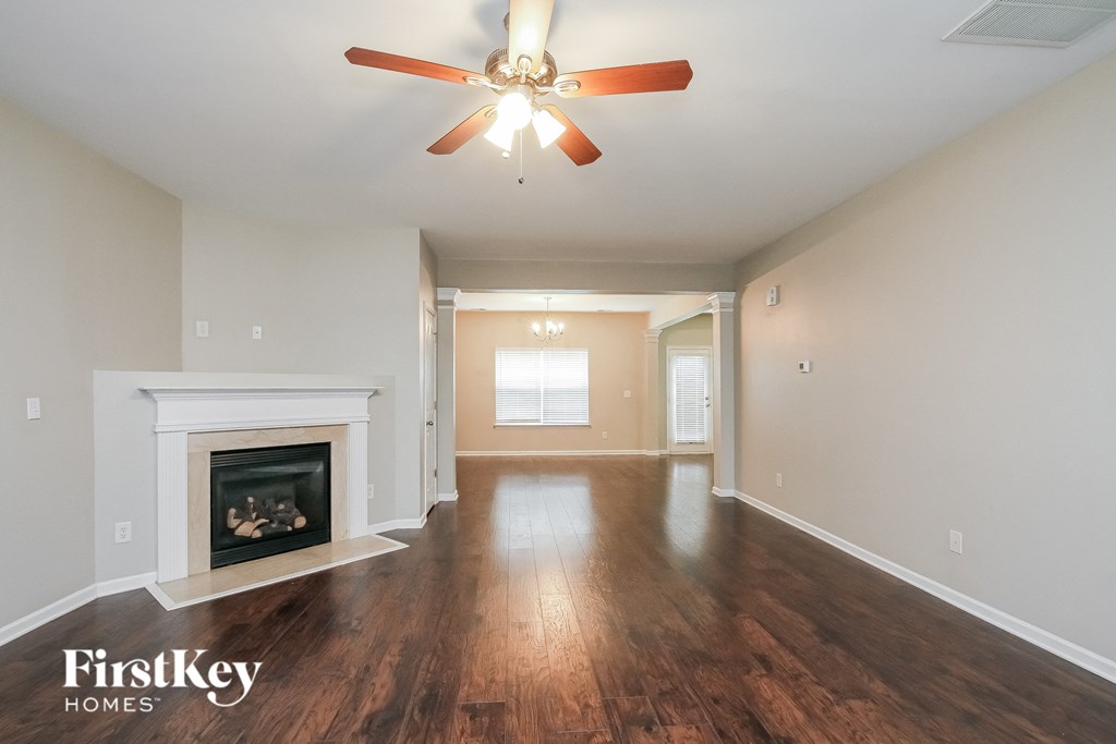 A spacious room with a fireplace and a ceiling fan.