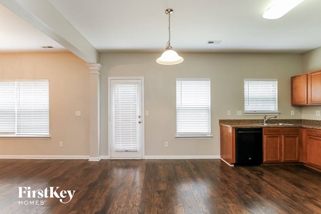 A kitchen with wooden floors and a black trash can.