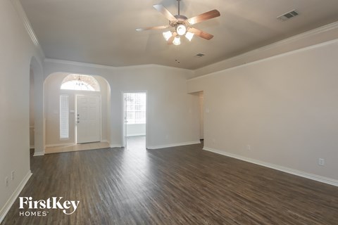 the living room of an empty house with a ceiling fan