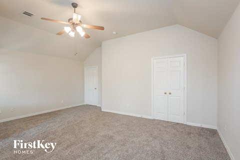 a bedroom with white walls and carpet and a ceiling fan