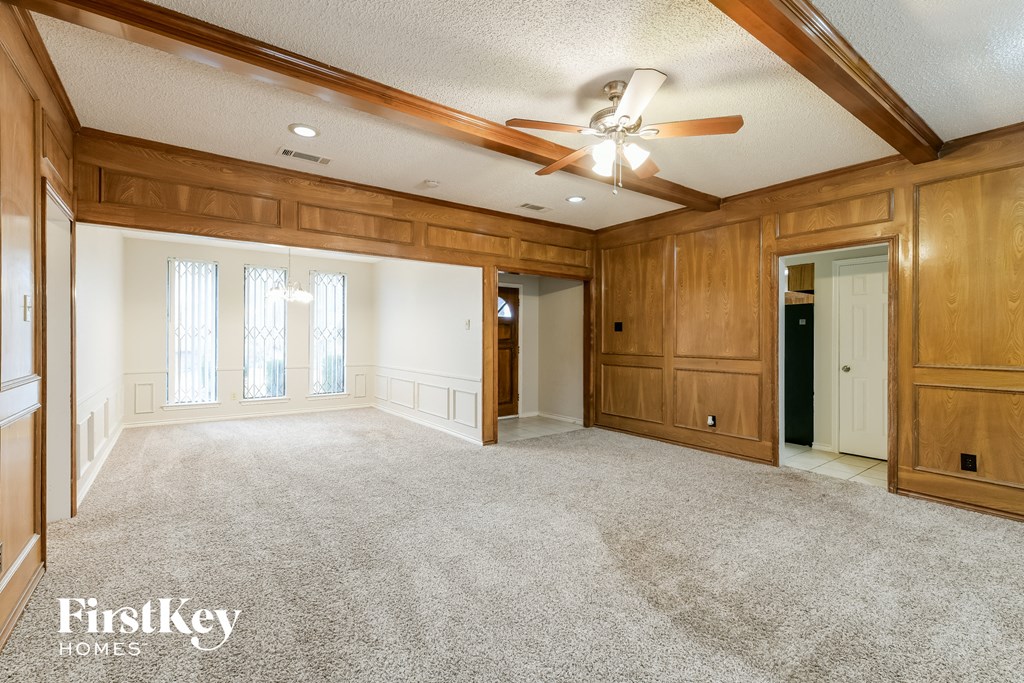 A spacious room with wooden walls and a ceiling fan.