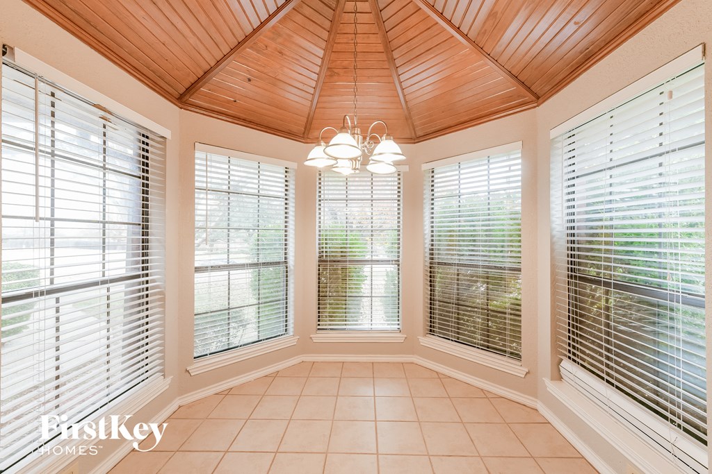 A sunroom with a wooden ceiling and white blinds.