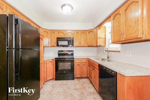 A kitchen with wooden cabinets and a black refrigerator.
