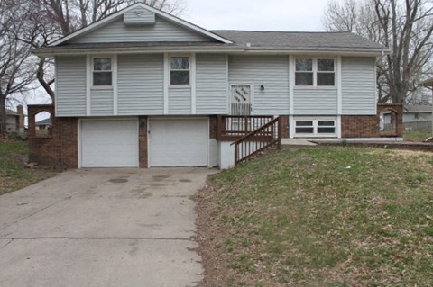 A house with a grey roof and white garage doors.