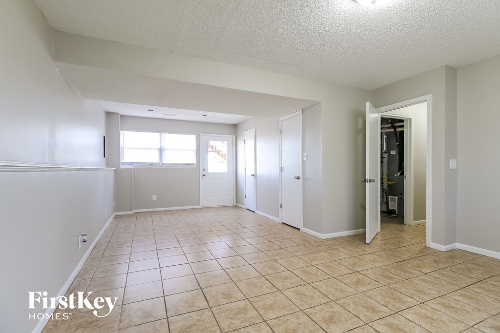 an empty living room with tiled floors and white walls