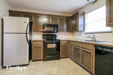 a kitchen with brown cabinets and black appliances and a refrigerator
