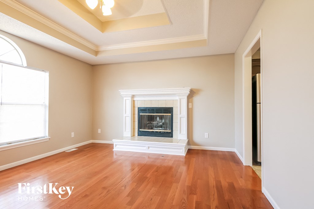 an empty living room with a fireplace and wooden floors