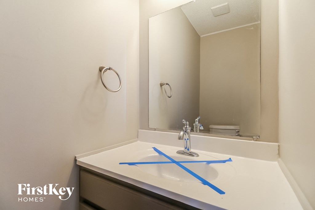 a bathroom with a sink and a mirror with blue construction tape on it