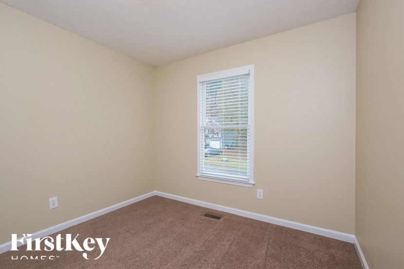 a bedroom with beige carpet and a window