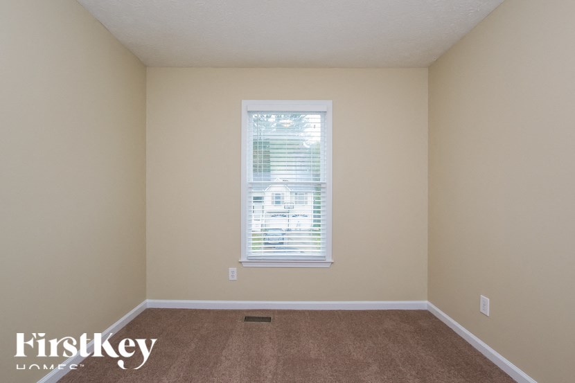 a bedroom with a window and a carpeted floor