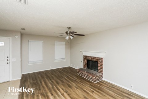 A living room with a fireplace and a ceiling fan.