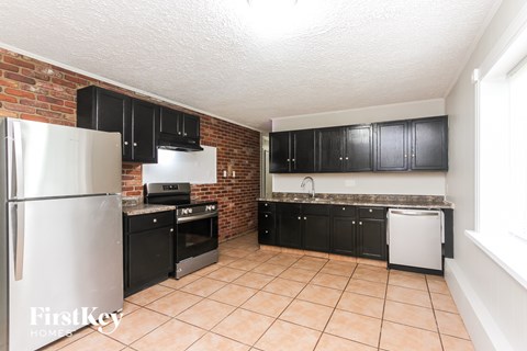 A kitchen with black cabinets and a white refrigerator.