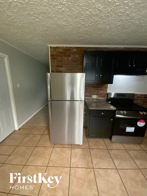 A kitchen with a stainless steel refrigerator and black cabinets.
