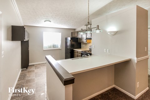 A kitchen with a white counter top and a black fridge.
