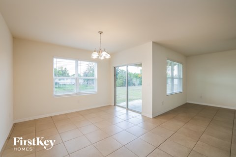 A spacious room with a chandelier and a sliding glass door leading to a backyard.