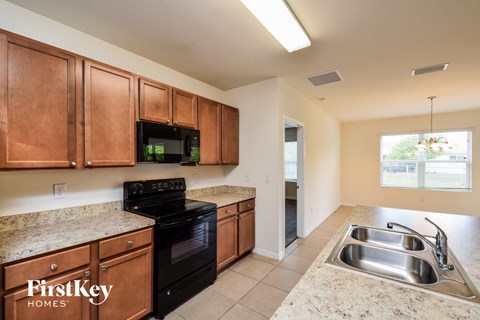 A kitchen with brown cabinets and a black stove top oven.