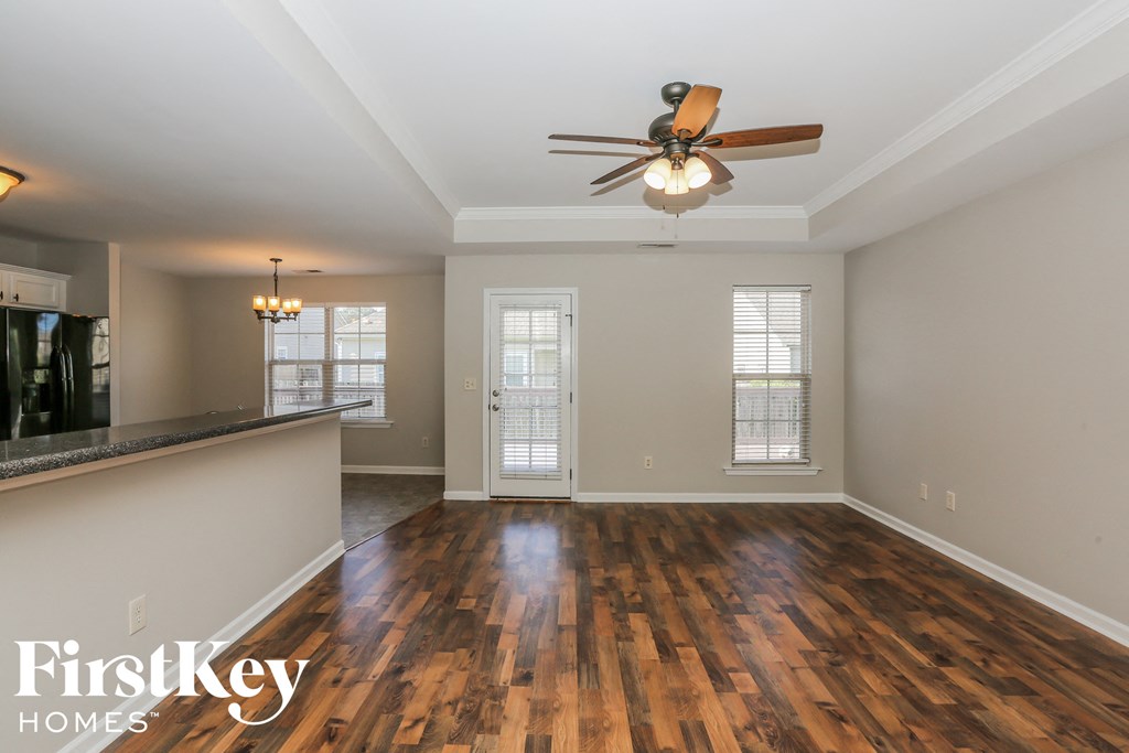 an empty living room with wood flooring and a ceiling fan